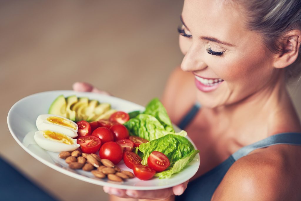 Picture of adult woman eating healthy lunch and sitting on yoga mat