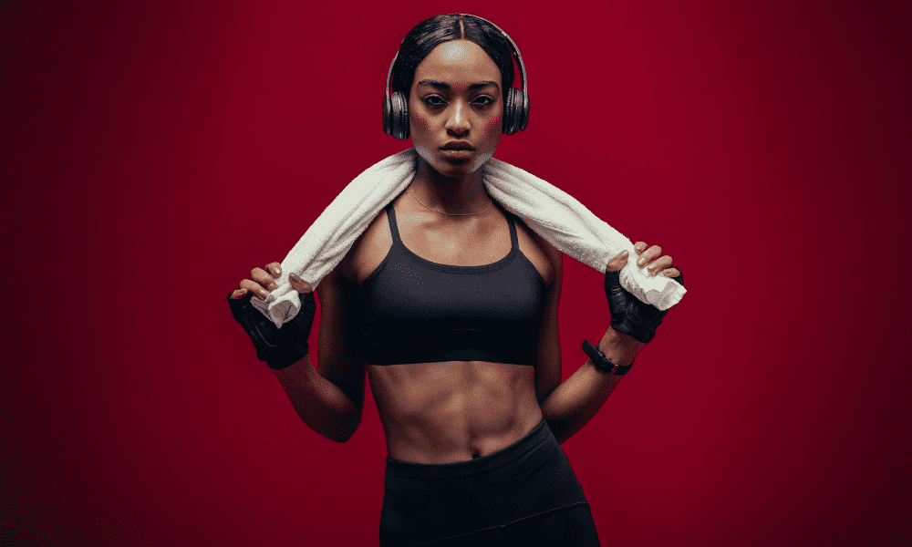 african american woman with headphones and a towel working out