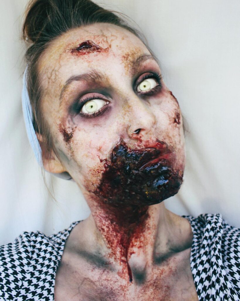 A person with zombie makeup, featuring rotting flesh, bloody wounds, and pale lifeless eyes for a gory undead look.