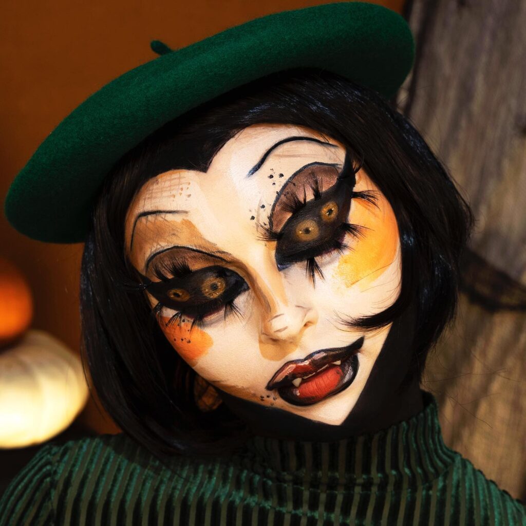 A person with vintage doll-inspired makeup, featuring exaggerated eyes, orange blush, black detailing, and a green beret for a creepy, worn doll look.