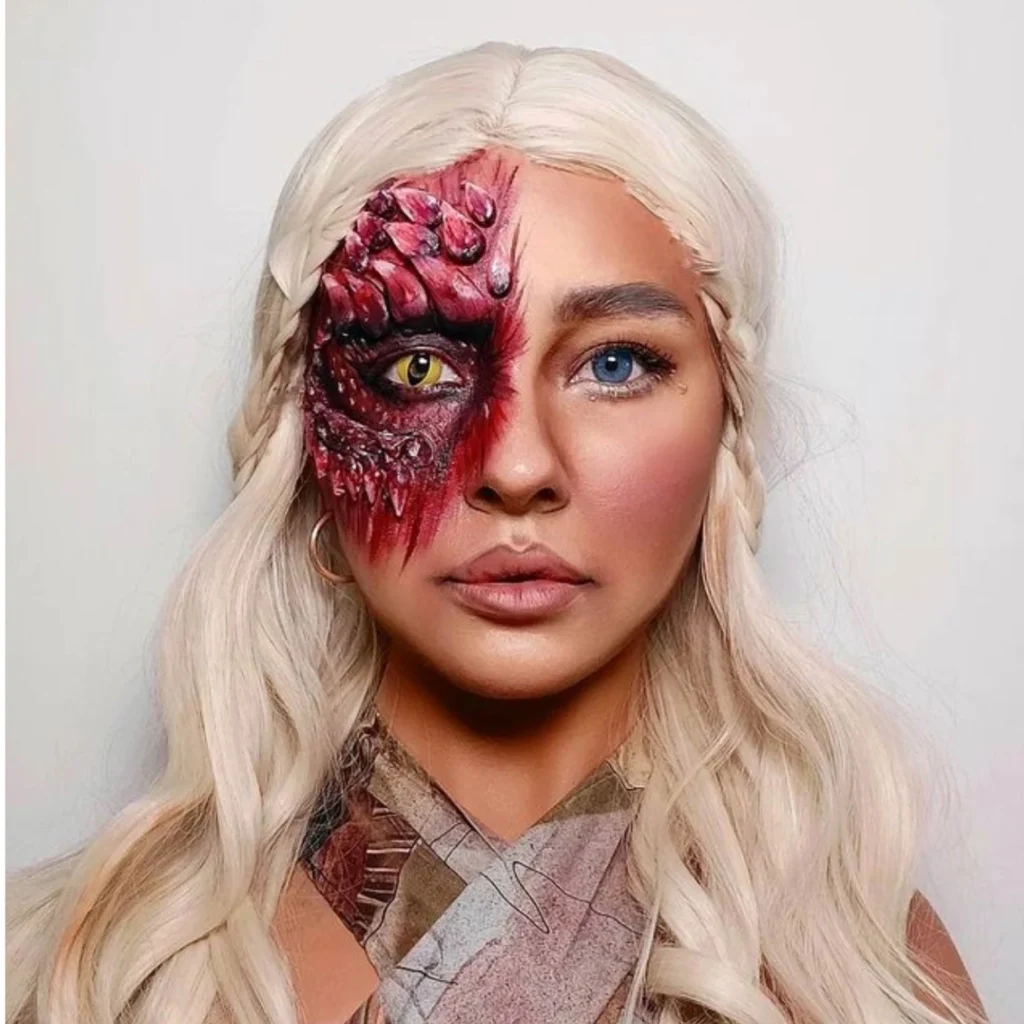 Close-up of a woman with Halloween makeup that transforms half of her face into a dragon, featuring scaly textures, a yellow reptilian eye, and red accents, while the other half remains human with a blue eye. The look is a stunning blend of fantasy and reality.