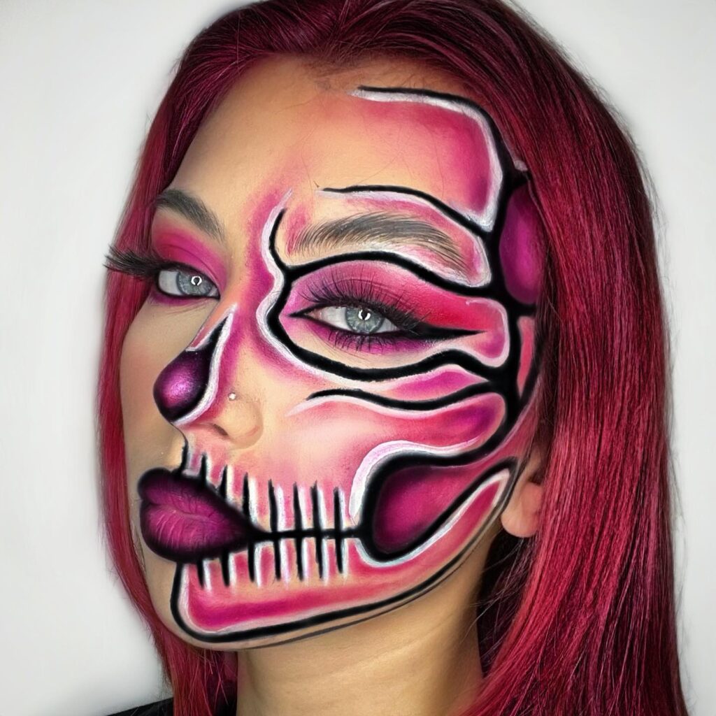 Person wearing neon pink skull-themed Halloween makeup with black and white contouring, vibrant eye makeup, and long lashes for a glowing skeleton effect.