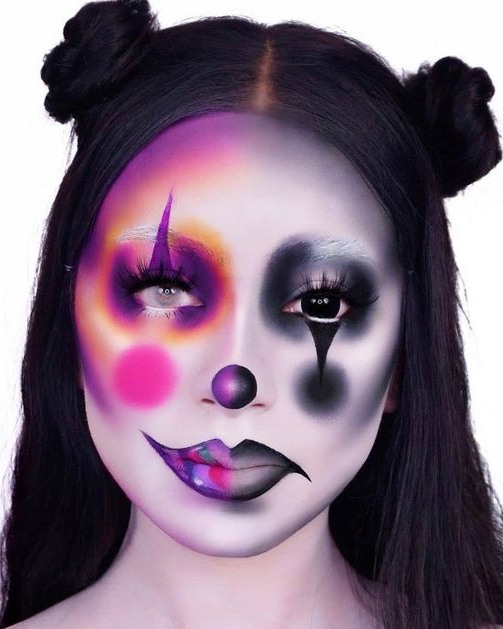 A person with neon-colored clown makeup, featuring vibrant pinks and purples on one side and dark smokey tones with black accents on the other side.