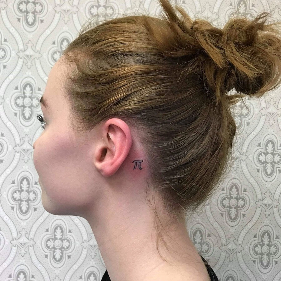 Side view of a Pi (π) symbol tattoo behind the ear on a woman with her hair tied up in a bun.