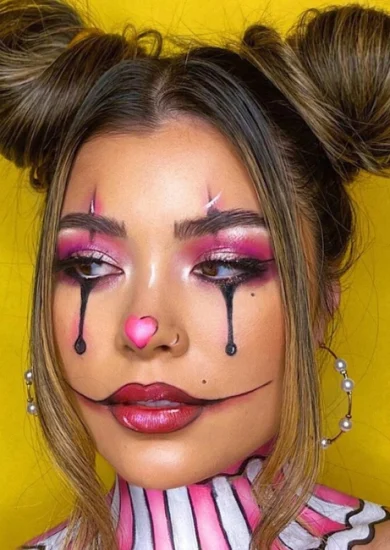 Creative Halloween makeup ideas featuring a pastel clown-inspired look with bold pink eyeshadow, black teardrop accents, and a heart-shaped nose for a playful and striking Halloween appearance.