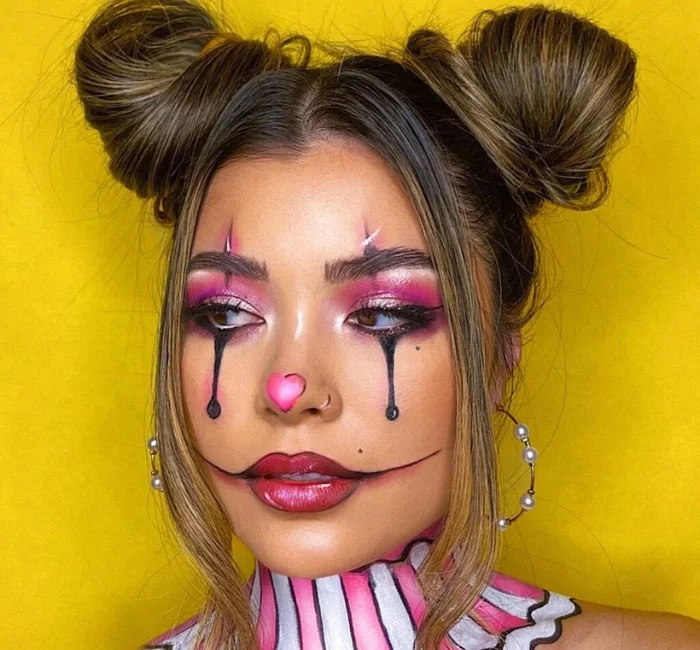 Creative Halloween makeup ideas featuring a pastel clown-inspired look with bold pink eyeshadow, black teardrop accents, and a heart-shaped nose for a playful and striking Halloween appearance.