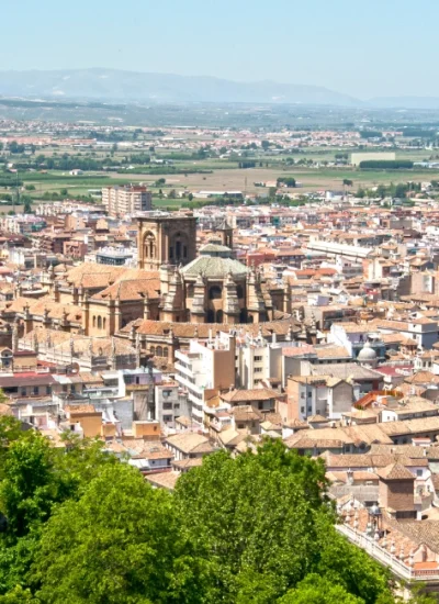 Stunning aerial view of Granada, Spain, showcasing the historic cityscape with the majestic Cathedral in the foreground, set against the backdrop of the Sierra Nevada mountains. Perfect depiction of 'things to do in Granada Spain.