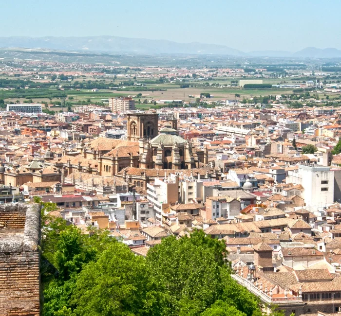 Stunning aerial view of Granada, Spain, showcasing the historic cityscape with the majestic Cathedral in the foreground, set against the backdrop of the Sierra Nevada mountains. Perfect depiction of 'things to do in Granada Spain.