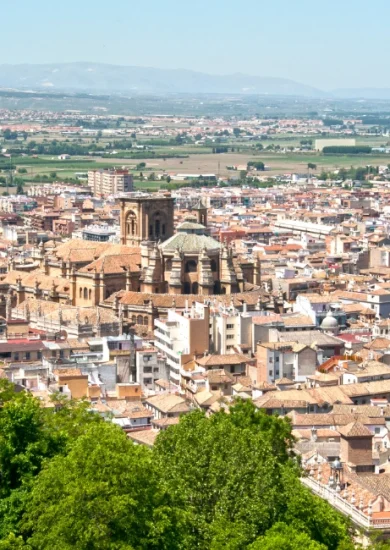 Stunning aerial view of Granada, Spain, showcasing the historic cityscape with the majestic Cathedral in the foreground, set against the backdrop of the Sierra Nevada mountains. Perfect depiction of 'things to do in Granada Spain.