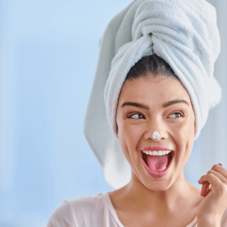 lady with white towel on her head moisturizing her face